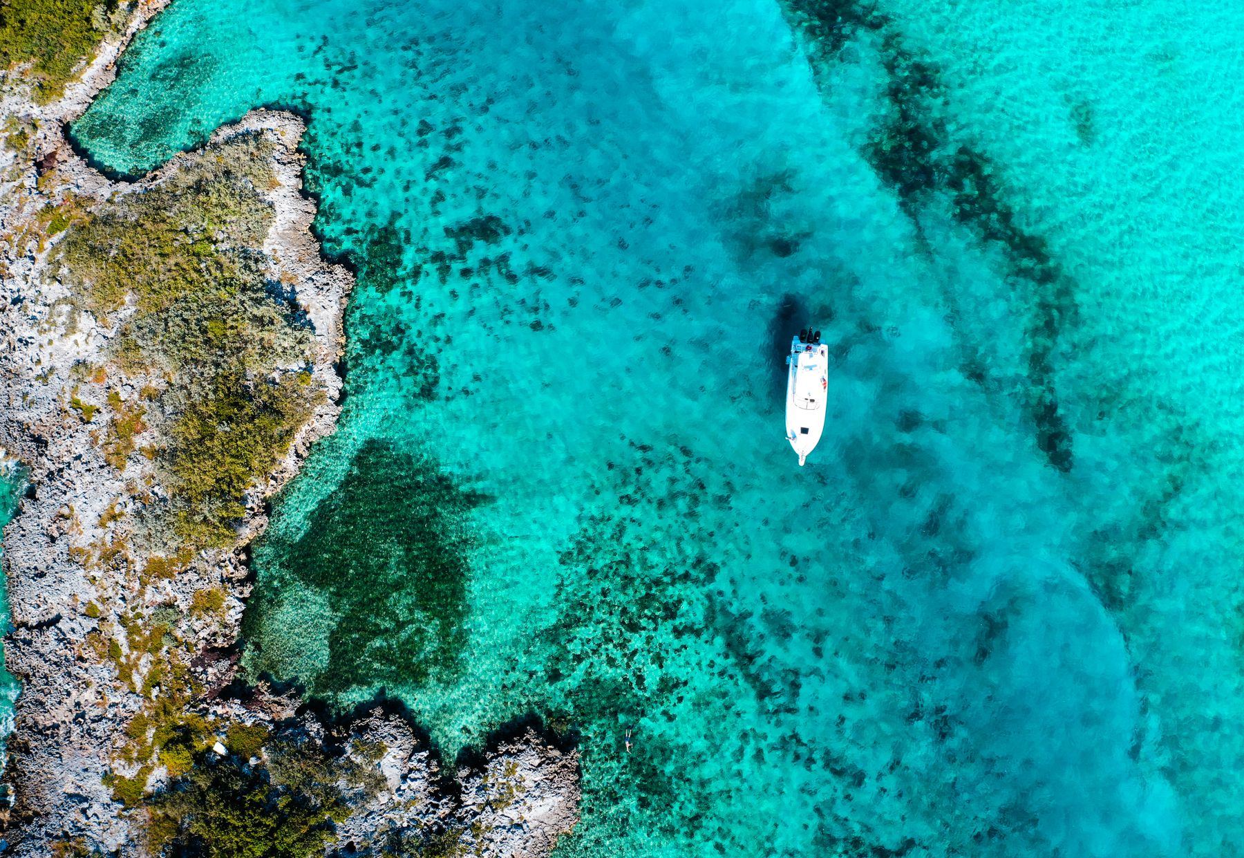 Aerial view of a charter boat anchored over turquoise reef flats