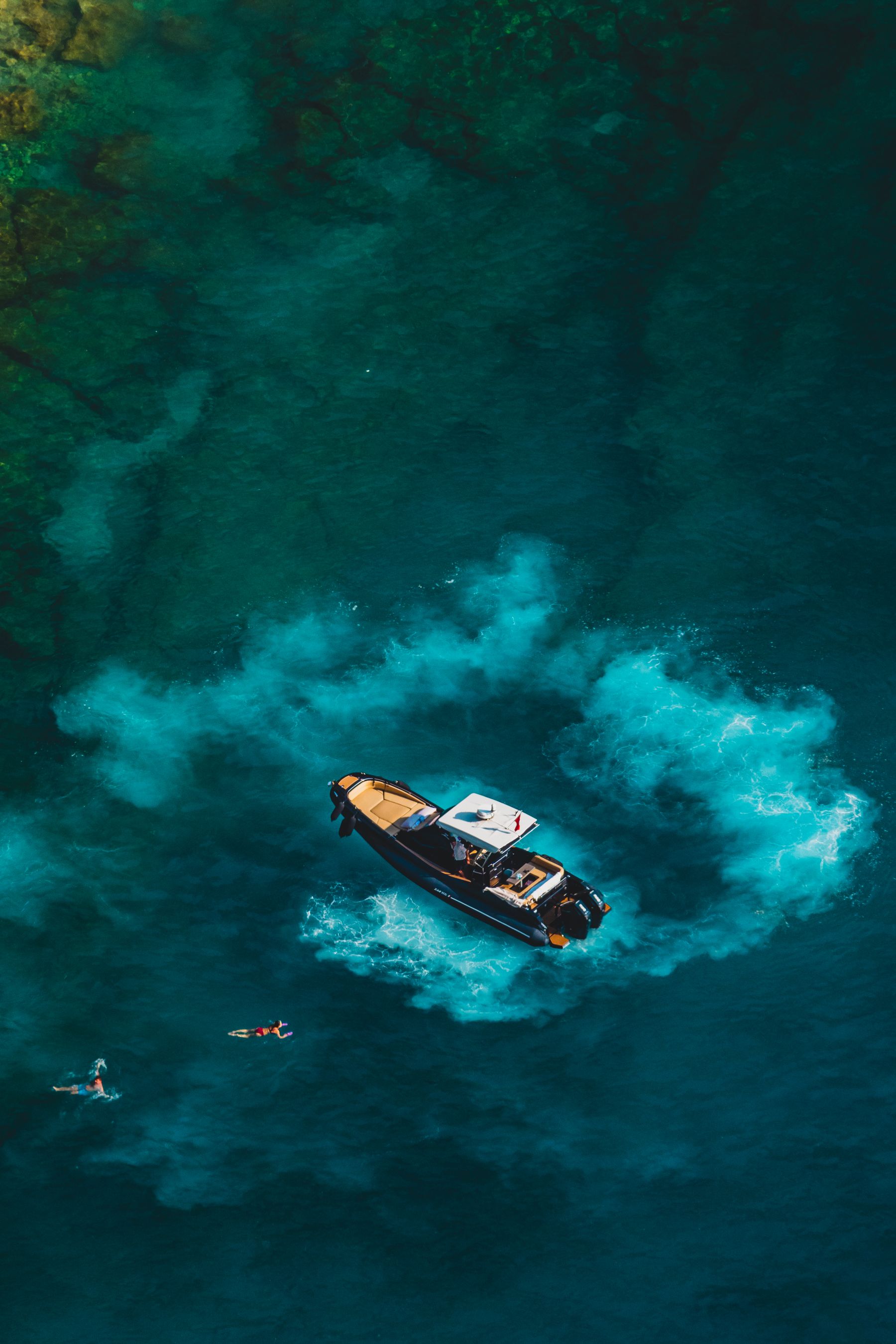 Tender idling over clear water with swimmers alongside