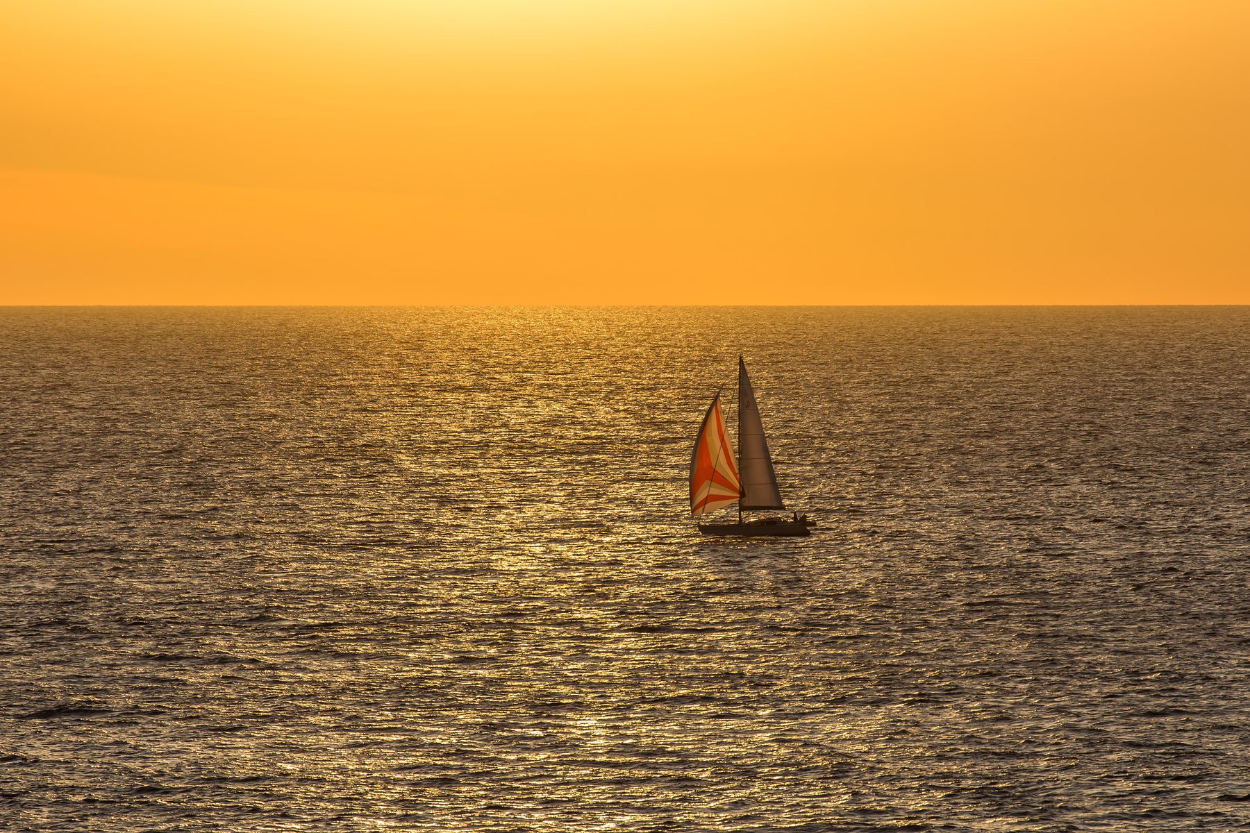 Boat silhouetted against a golden ocean sunset